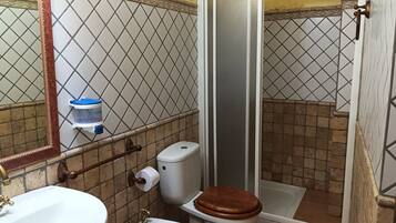 Un baño con inodoro, bidé, lavamanos y ducha.