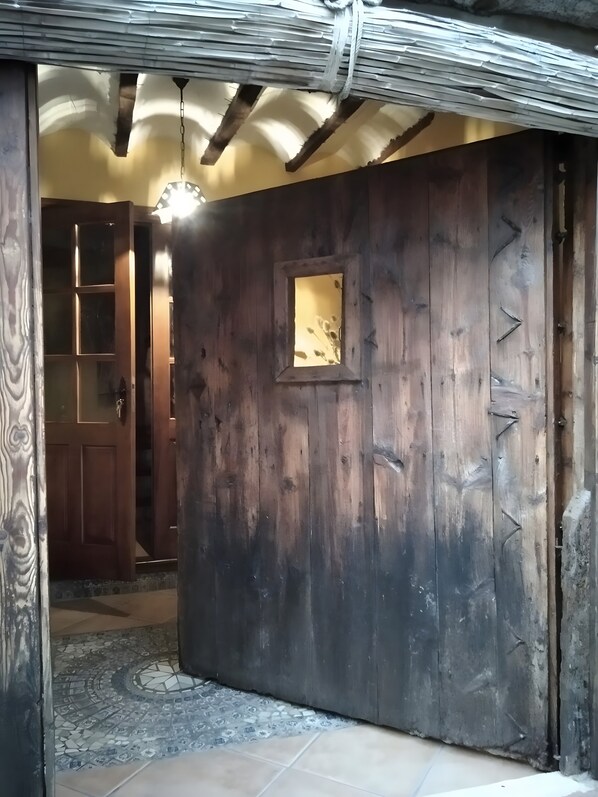 A wooden door with a small window, a tiled floor, and a ceiling with exposed beams.