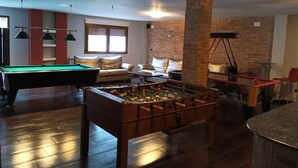 A pool table, foosball table, and a sofa in a room with brick walls and a window. - Country House 'La Cisterna II' (Pina de Montalgrao)