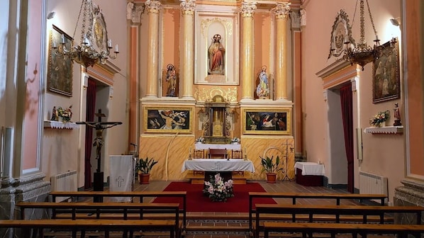 Interior de una iglesia con altar, bancas y estatuas religiosas.