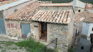 Un pequeño edificio de piedra con techo de tejas, una puerta a la vista y una escalera que lleva a la entrada.