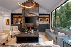 A modern living room with a fireplace, built-in shelves, a large window, and a view of the outdoors.
