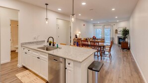 A modern kitchen with a central island, stainless steel dishwasher, and pendant lights. - Luxe Condo-Shuttle & Amenities (Lincoln)