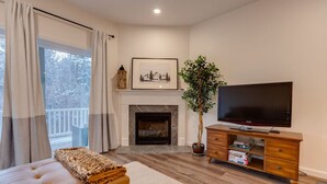 A cozy living room with a fireplace, a television, a large potted plant, and a comfortable sofa. - Luxe Condo-Shuttle & Amenities (Lincoln)