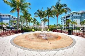 Stroll around the serene water feature surrounded by a circular walkway and lush palm trees.