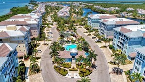 Et resort med flere bygninger, en central pool og udsigt til havet.