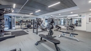 Un gimnasio moderno con diverso equipo de ejercicio, incluyendo cintas de correr, máquinas de pesas y pesas libres.