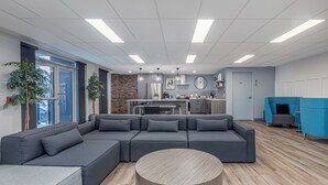 Una sala de estar moderna con un sofá modular, una mesa de centro redonda y una cocina al fondo.