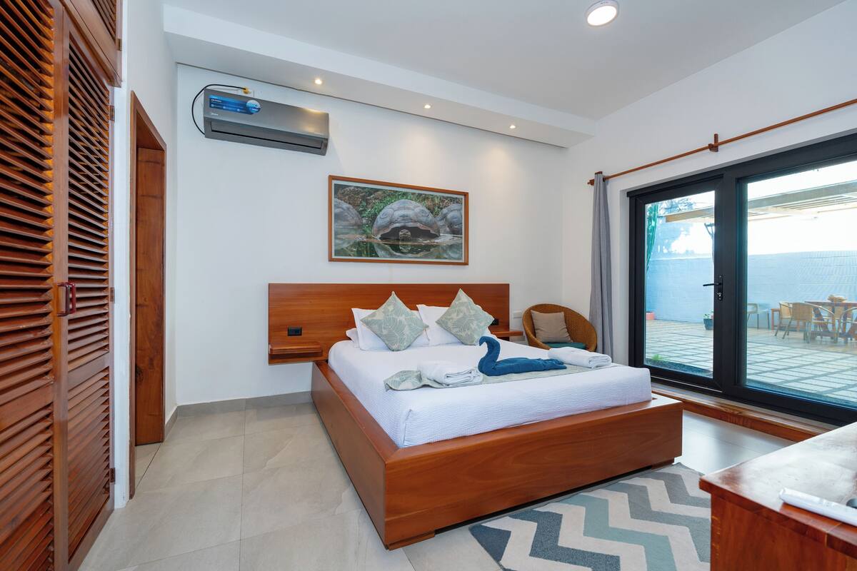 Une chambre avec un lit en bois, une grande fenêtre et une vue sur la mer.