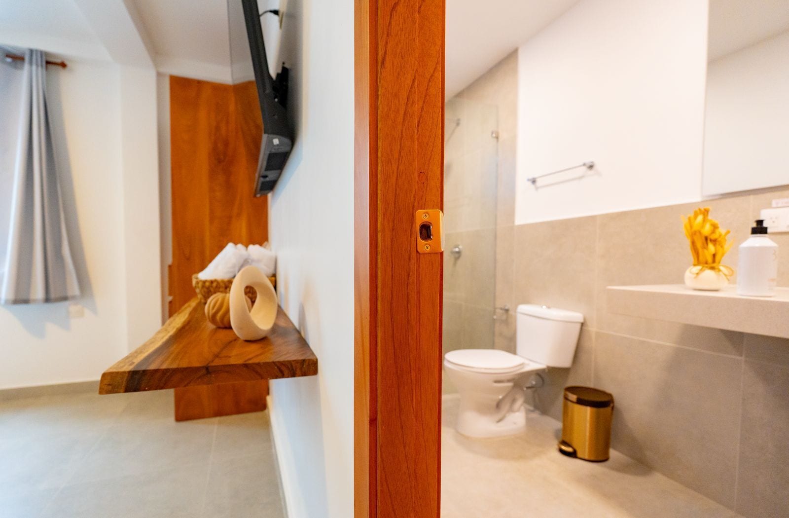 Un baño moderno con tocador de madera, inodoro y zona de ducha.