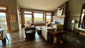 A spacious living room with a fireplace, large windows, and a view of the outdoors.