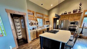A modern kitchen with wooden cabinets, a large island, and stainless steel appliances.