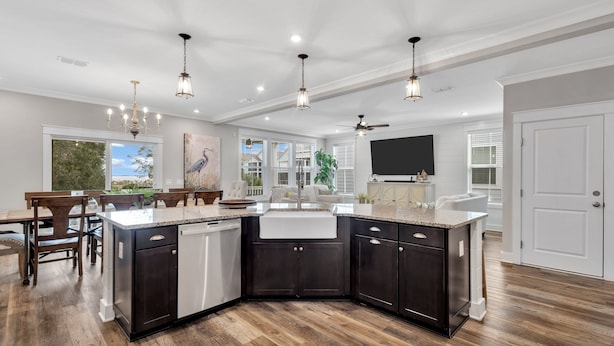 Une cuisine moderne avec des meubles de couleur sombre, un îlot central et des luminaires suspendus.