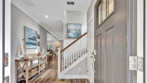 Un couloir avec un banc en bois, un escalier et, au fond, un coin repas.