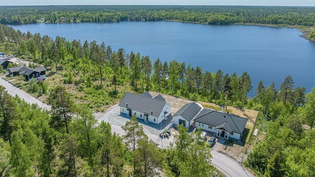 Ett bostadsområde med hus som ligger nära en stor sjö, omgivet av tät skog.