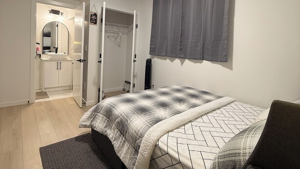 A bedroom with a bed, bedside table, and a coffee machine. - 2-Bed, 2-Bath Home: Perfect for Work, Relaxation, and Exploring Calgary & Banff. (Calgary)
