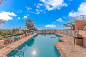 Una piscina con sillones de descanso, una torre de salvavidas y vistas al océano.