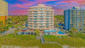 Ein mehrstöckiges Hotel mit Innenhof, Pool und Strandbereich.