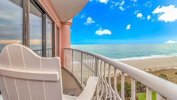 Ein Balkon mit Blick auf Strand und Meer.