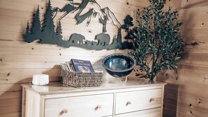 A wooden cabinet with a decorative wall piece, a bowl, a basket with books, and a potted plant.