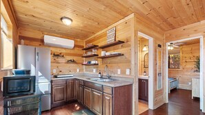 A wooden cabin interior with a kitchen featuring a refrigerator, microwave, and wooden cabinets.