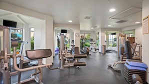 Un gimnasio con diferentes máquinas de ejercicio, una banca y un espejo.