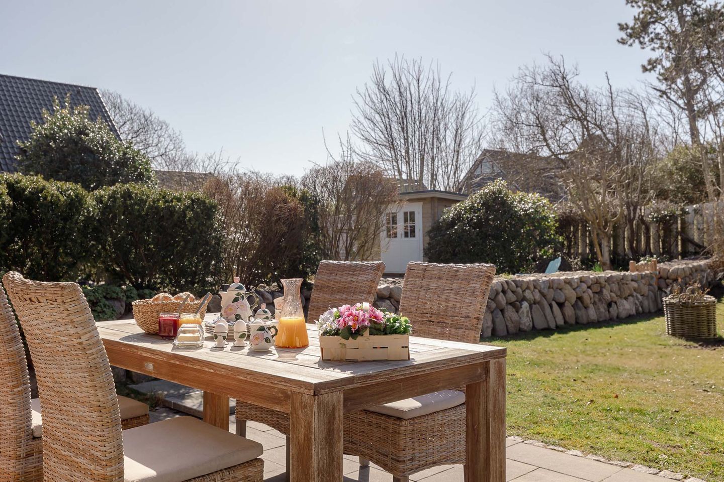 An outdoor dining area with wicker furniture and a table set for breakfast.