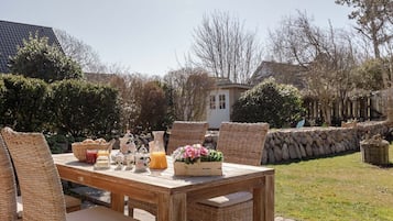 An outdoor dining area with wicker furniture and a table set for breakfast.