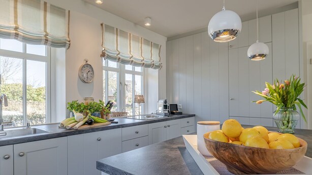 A modern kitchen with a large island, white cabinetry, and a view of the outdoors.