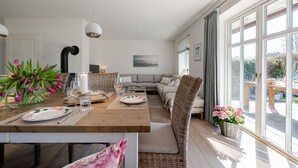 A modern living room with a dining area, large windows, and a view of the outdoors.