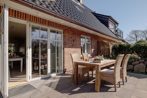 Une maison avec un patio, une table à manger avec des chaises et une porte-fenêtre coulissante donnant sur une pièce.