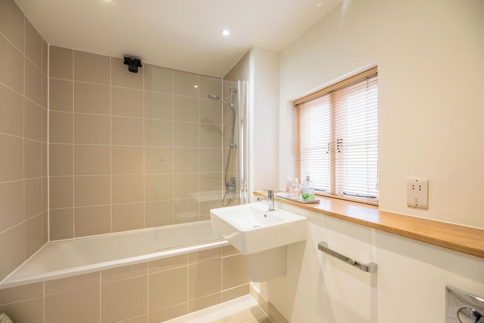 A modern bathroom with a bathtub, shower, and sink.