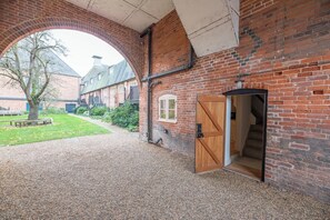 Ein Backsteinhaus mit großem Bogenportal, einer Holztür und einem Kieshof.