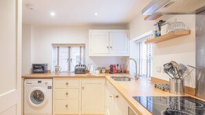 A compact kitchen with a washing machine, a coffee maker, and a toaster. - Kiln House, Snape Maltings (Snape)