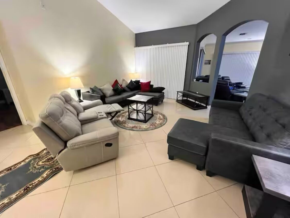 A living room with a grey sofa, a smaller grey armchair, a coffee table, and a rug.