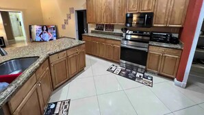A kitchen with wooden cabinets, a stainless steel sink, a microwave, and an oven.