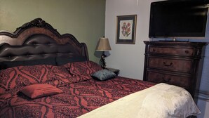Un dormitorio con una cama grande, un aparador, una lámpara y un televisor en la pared.