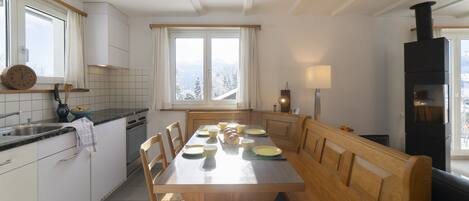 A modern kitchen with a central island, wooden benches, and a view of the outdoors.