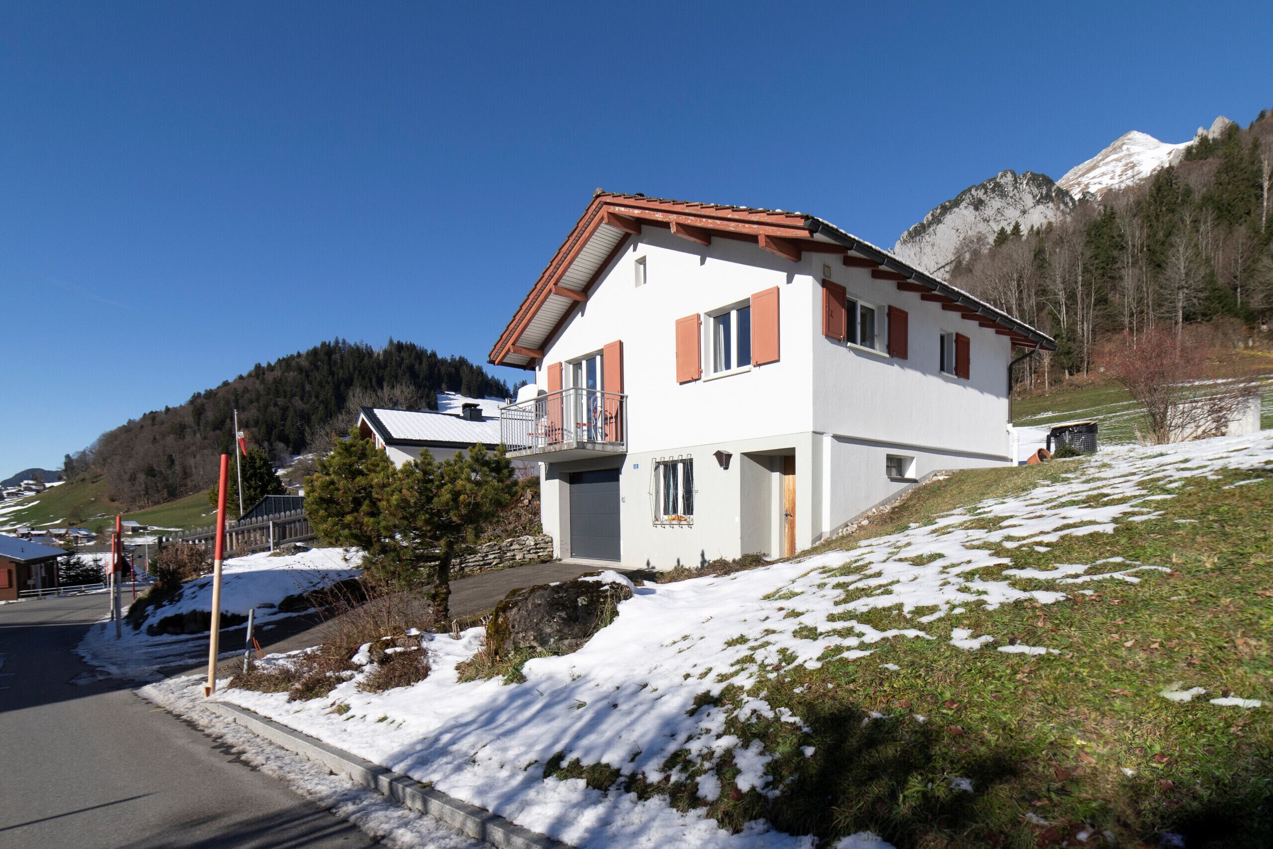 Ein zweistöckiges Haus mit rotem Dach, weißen Wänden und einem Balkon.