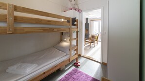 Habitación con literas de madera, una mesita pequeña y una silla.