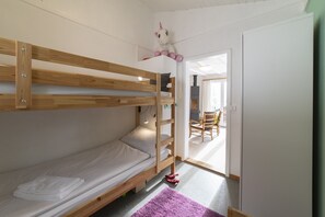 Habitación con literas de madera, una mesita pequeña y una silla.