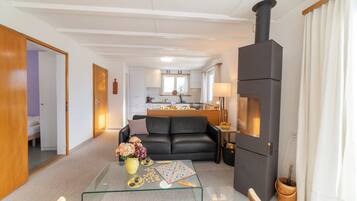 Ein modernes Wohnzimmer mit einem Glastisch, einem schwarzen Sofa und einem Kamin.