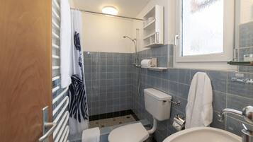Ein kleines Badezimmer mit Toilette, Bidet und Waschbecken, ausgestattet mit blauen Fliesen und einem Fenster.