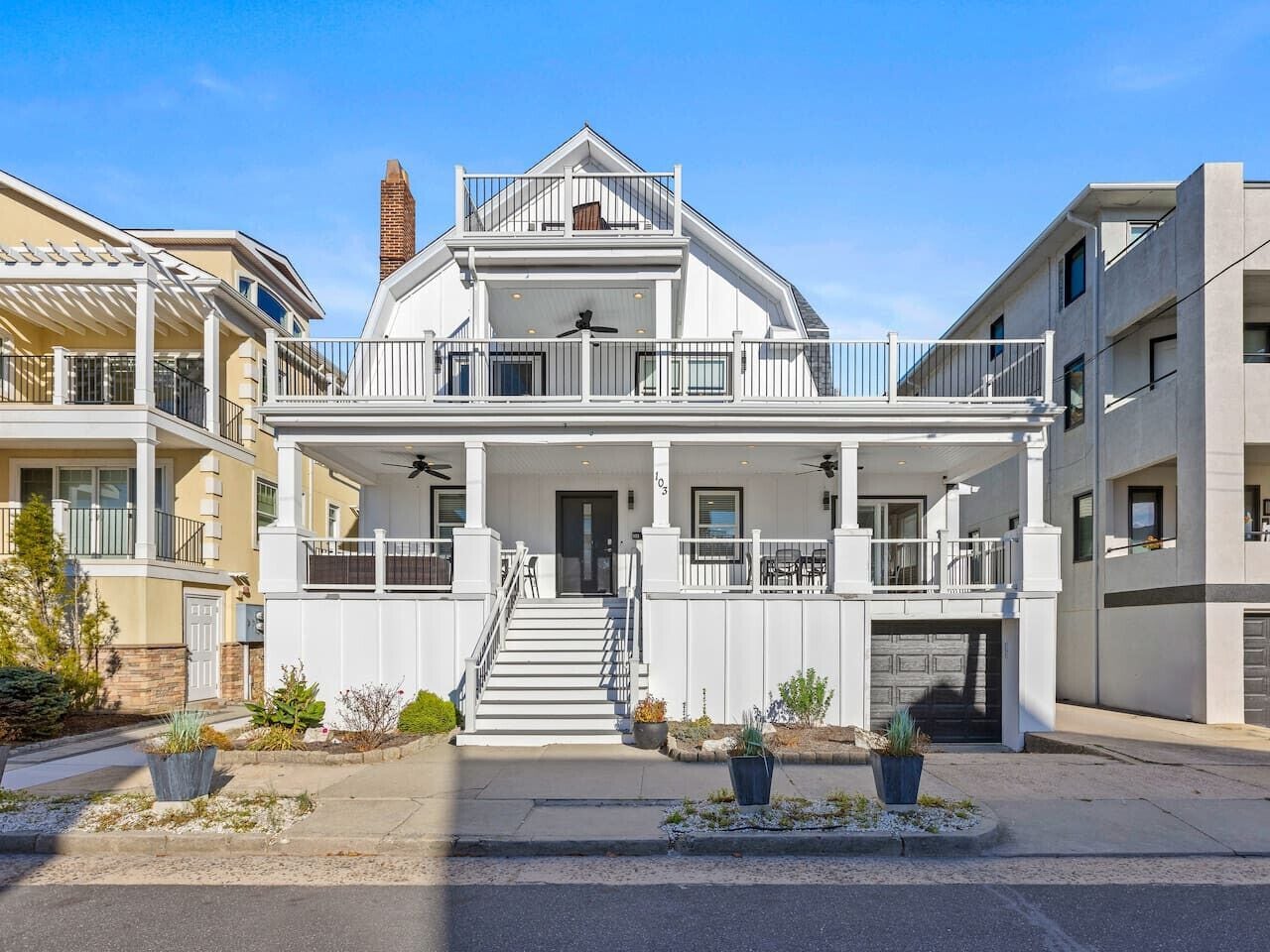 A two-story residential building with a front porch, a staircase, and a garage.