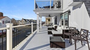 A balcony with outdoor seating, a railing, and a view of the street.