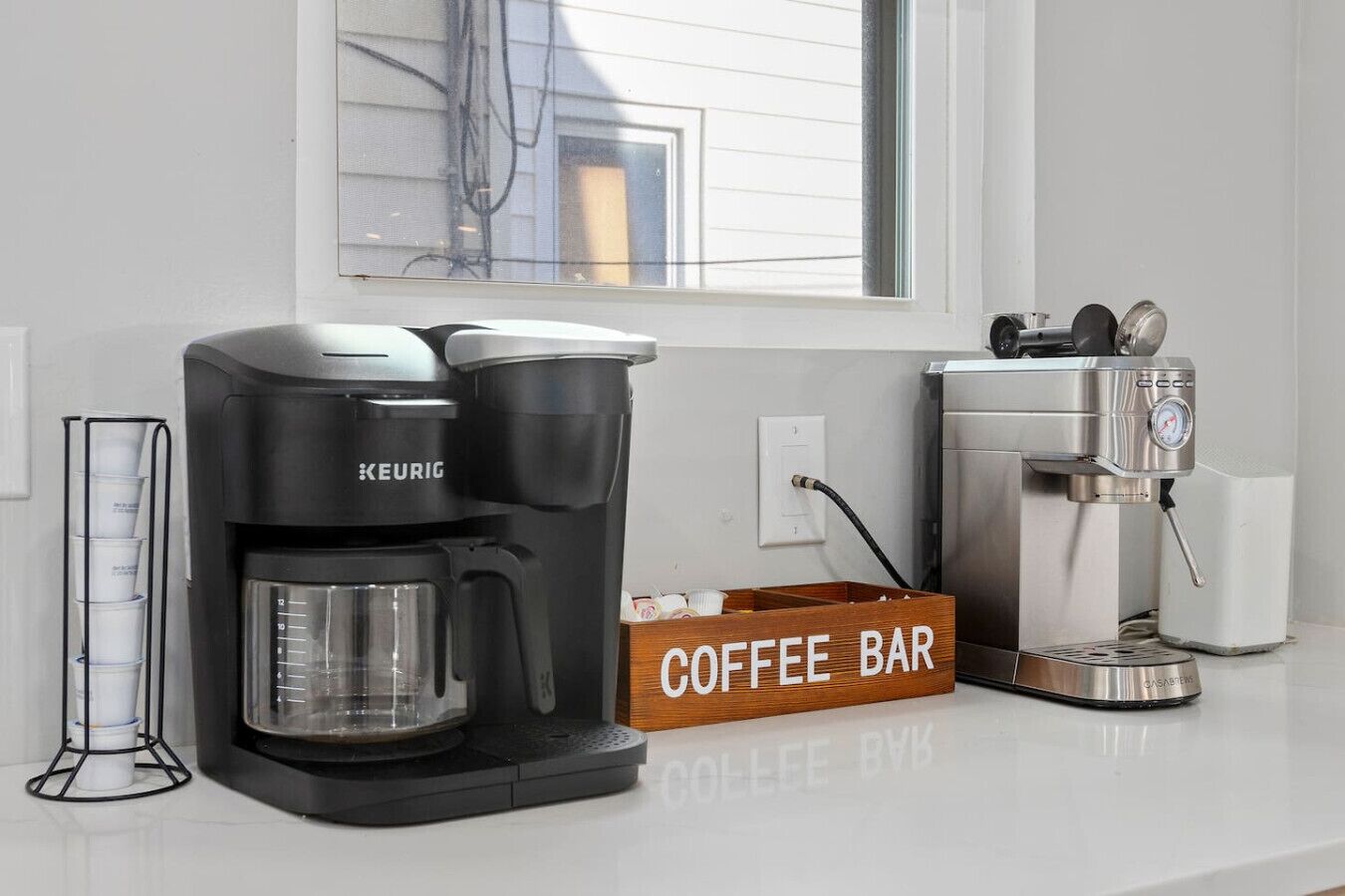 Een koffiezetapparaat, een koffiemolen en een bord met daarop 'Coffee Bar' in een keuken.