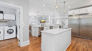 A modern kitchen with a central island, stainless steel appliances, and a laundry area.