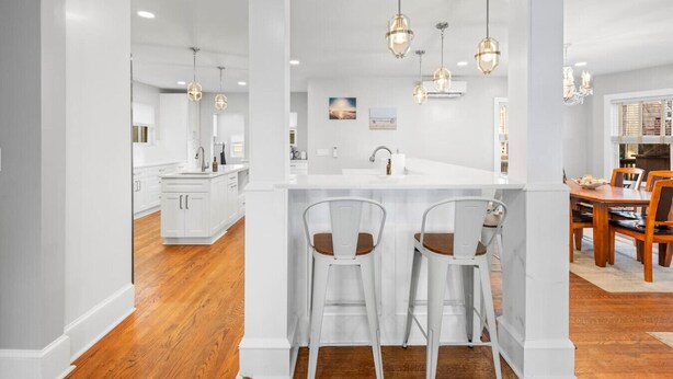 A modern kitchen with white cabinetry, a central island, and pendant lighting.