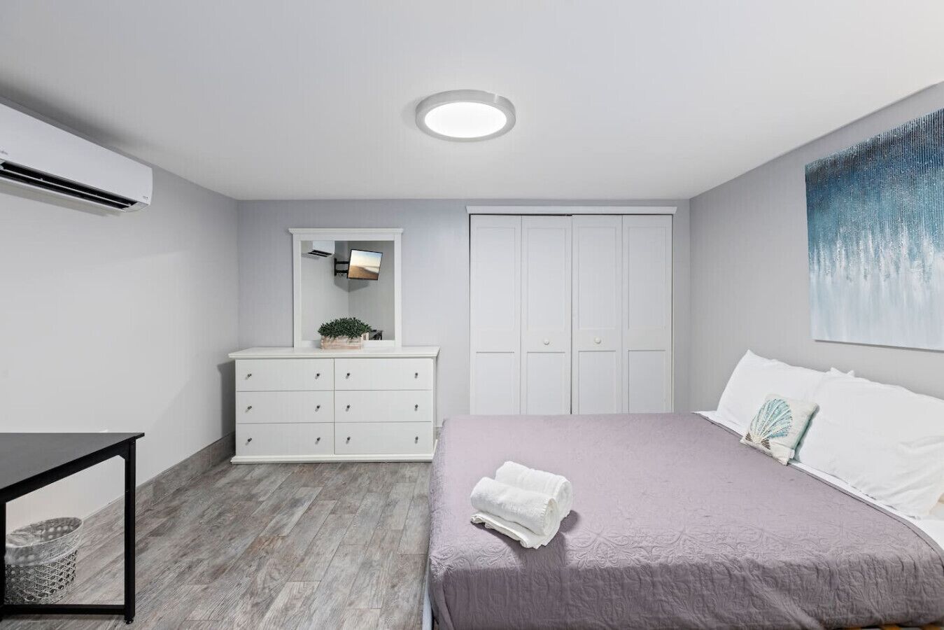 A modern bedroom with a bed, dresser, and a large window.