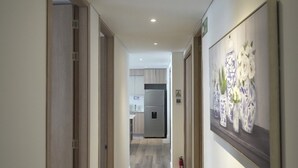 A hallway leading to a kitchen with a refrigerator and cabinets. - Modern new 3 bedroom apartment 5min walk to beachl/shops/restaurants (San Andrés)